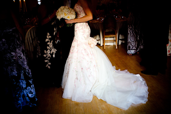 bride wearing a champagne ball gown style dress with dark pink and green designs holding an ivory rose bouquet - photo by New Mexico based wedding photographers Twin Lens
